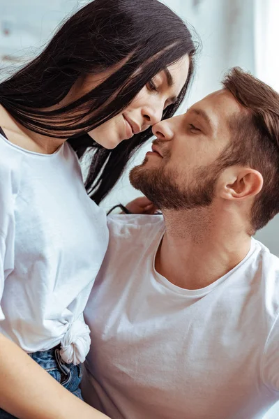 Homem bonito abraçando e beijando mulher bonita e morena em t-shirt — Fotografia de Stock