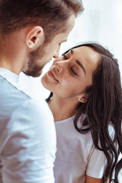 Handsome man and beautiful woman in t-shirt looking at each other and kissing — Stock Photo