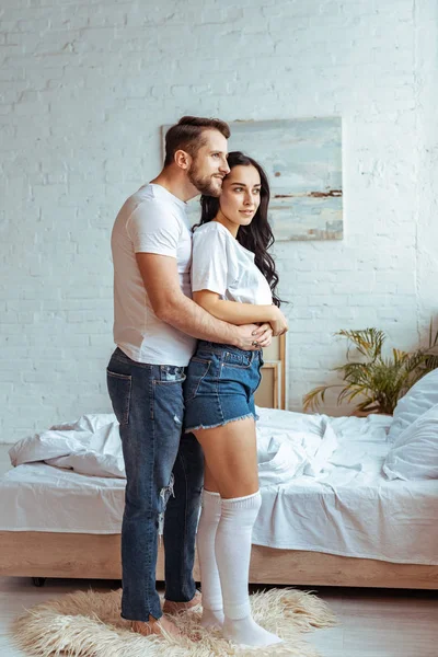 Schöner Mann in Jeans umarmt schöne und brünette Frau in T-Shirt und Shorts — Stockfoto