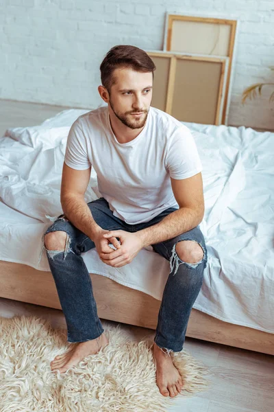 Good-looking man in white t-shirt and jeans looking away — Stock Photo