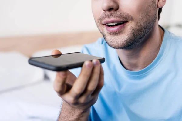 Selective focus of smiling man talking on smartphone by speakerphone — Stock Photo