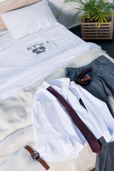 Suite e jornal de negócios sobre roupa de cama branca no quarto — Fotografia de Stock