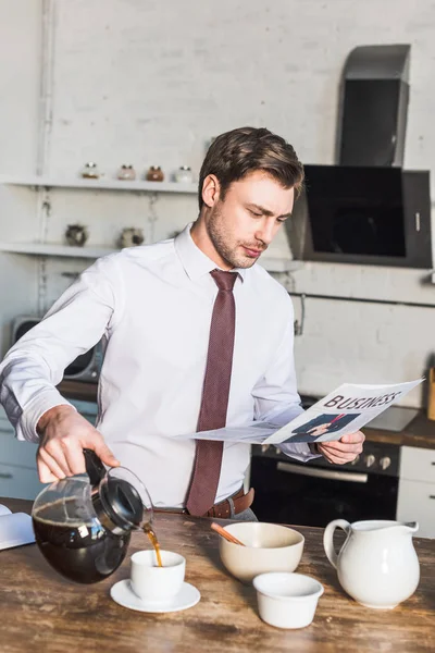 Bell'uomo che versa il caffè nella tazza e legge il giornale aziendale — Foto stock