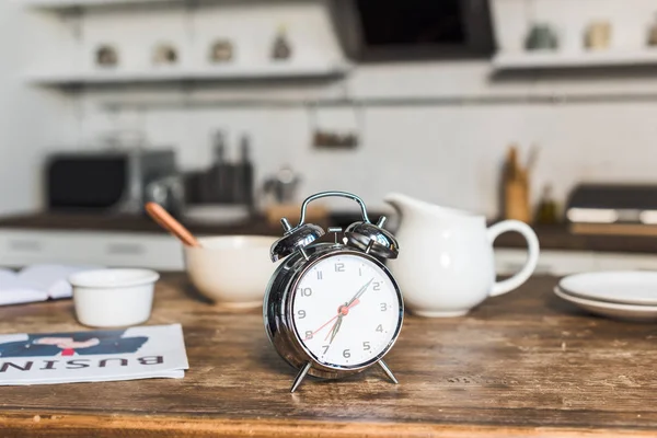 Selective focus of vintage alarm clock at wooden table in kitchen — Stock Photo