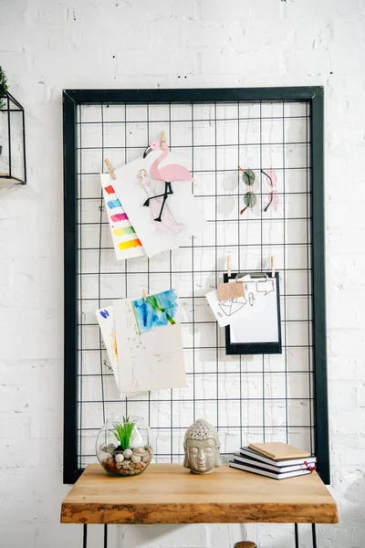 Pinnwand mit Zeichnungen und Brille und Holztisch im Teenagerzimmer — Stockfoto