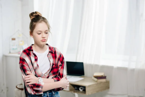 Nachdenklicher Teenager im karierten Hemd, der mit verschränkten Armen steht und nach unten schaut — Stockfoto