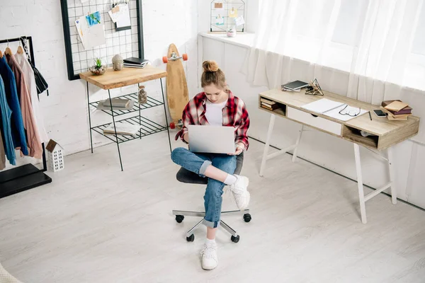 Teenager im rot karierten Hemd mit Laptop zu Hause — Stockfoto