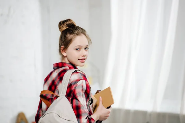 Teenage schoolgirl in checkered shirt with backpack holding books — Stock Photo