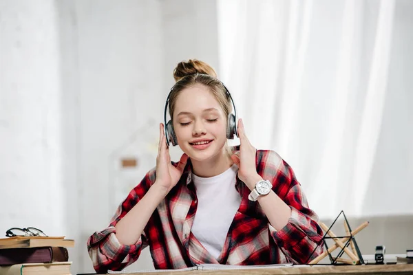 Alegre adolescente con camisa roja a cuadros escuchando música en auriculares - foto de stock