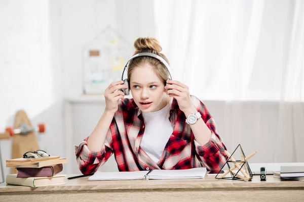 Fröhliches Teenager-Kind in rot kariertem Hemd, das über Kopfhörer Musik hört — Stockfoto