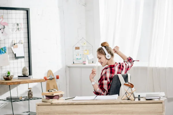 Fröhliches Teenager-Kind in rot kariertem Hemd, das über Kopfhörer Musik hört — Stockfoto