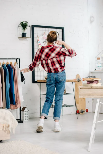 Back view of teenager in jeans listening music in headphones — Stock Photo