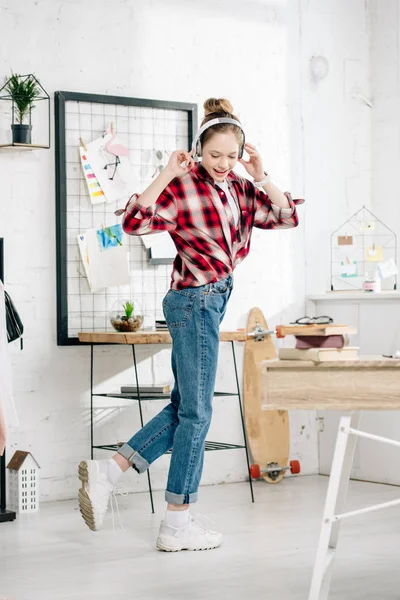 Full length view of teenager in jeans listening music in headphones — Stock Photo