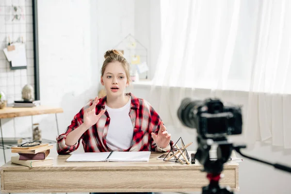 Подростковый блогер сидит за столом перед видеокамерой и снимает видео — стоковое фото