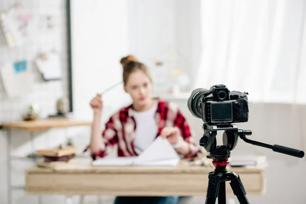 Блогер-підліток сидить за столом перед відеокамерою і робить відео — стокове фото