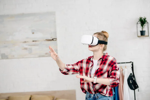 Teenager in red checkered shirt and vr headset gesturing at home — Stock Photo