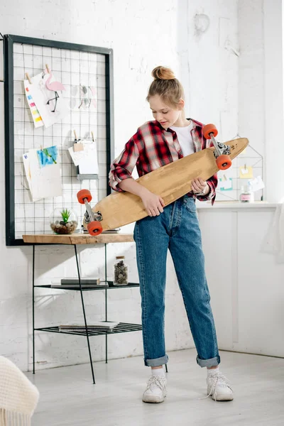 Повна довжина погляду підлітка в джинсах тримає Longboard на дому — стокове фото