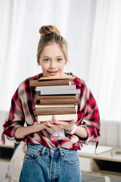 Teenage kid in red checkered shirt holding books at home — Stock Photo