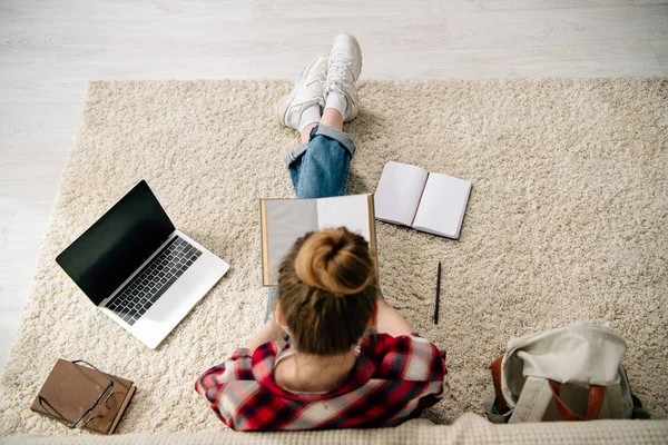 Вид зверху підлітка з книгами та ноутбуком з порожнім екраном робить домашнє завдання — стокове фото
