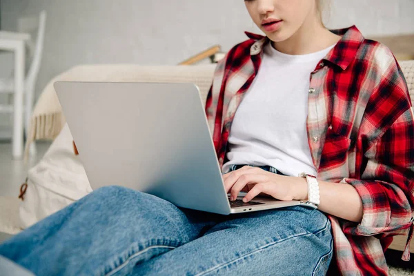 Vue recadrée de l'adolescent en chemise à carreaux à l'aide d'un ordinateur portable — Photo de stock