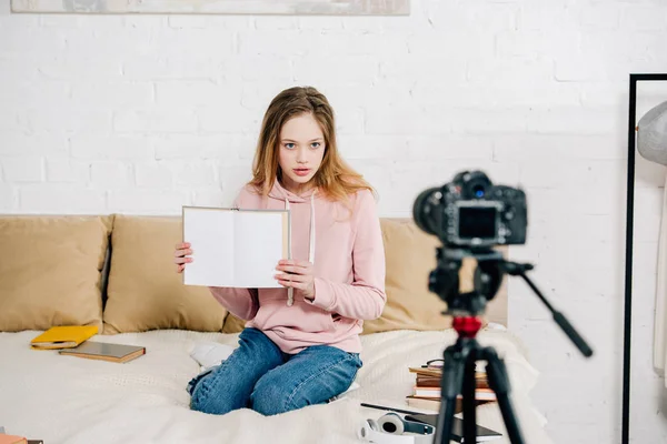 Блогер-підліток показує книгу з порожніми сторінками на відеокамеру — стокове фото