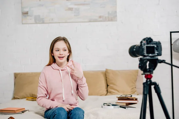 Joyful teenage blogger showing peace sign at video camera — Stock Photo