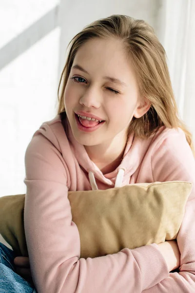 Criança adolescente sorridente abraçando almofada marrom e olhando para a câmera — Fotografia de Stock