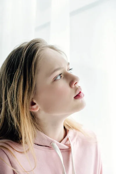 Pensive teenage kid in pink hoodie looking away — Stock Photo