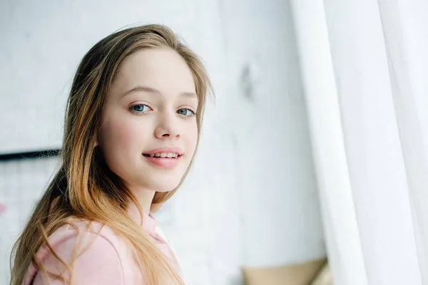 Joyful teenage kid in pink hoodie looking at camera with smile — Stock Photo