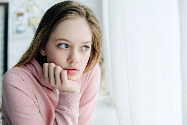 Pensive teenage propping face with hand and looking away — Stock Photo