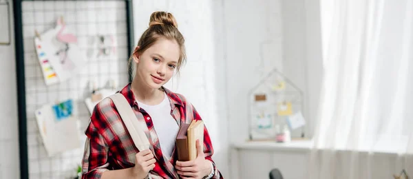 Panoramic shot of cute teenager kid with backpack holding books — Stock Photo