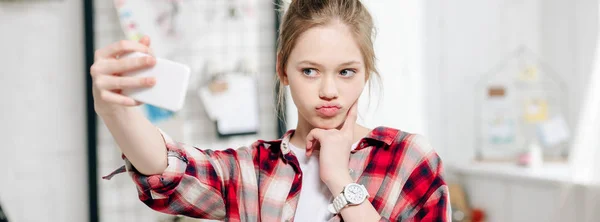 Foto panorámica de adolescente en camisa a cuadros tomando selfie en casa - foto de stock