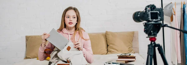 Panoramic shot of teenager holding book and backpack in front of video camera in bedroom — Stock Photo