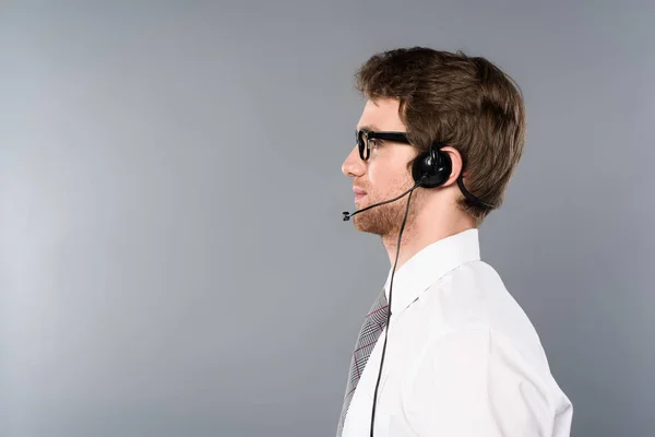 Vista lateral do operador de call center confiante no fundo cinza — Fotografia de Stock