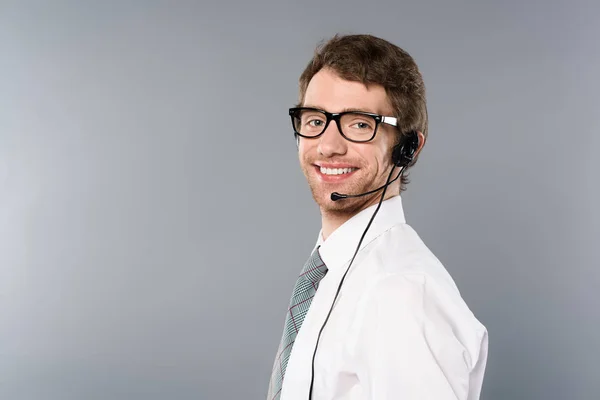 Sonriente operador de centro de llamadas en auriculares y gafas mirando a la cámara - foto de stock