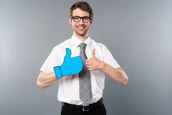Smiling businessman in glasses showing thumbs up on grey background — Stock Photo