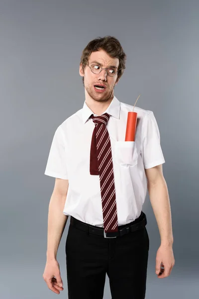 Confused businessman in glasses looking at dynamite in pocket — Stock Photo