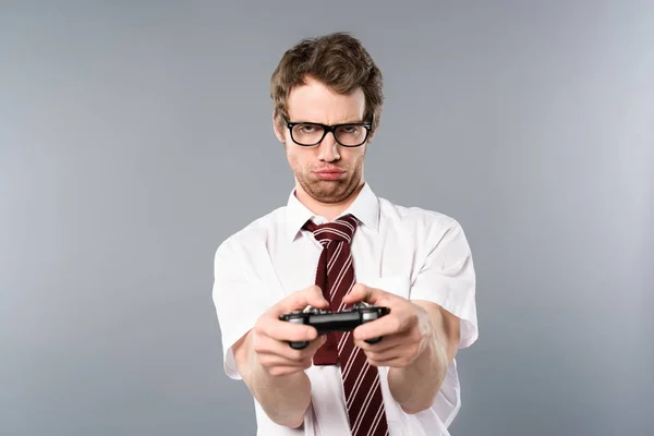Upset businessman playing video game with joystick on grey background — Stock Photo