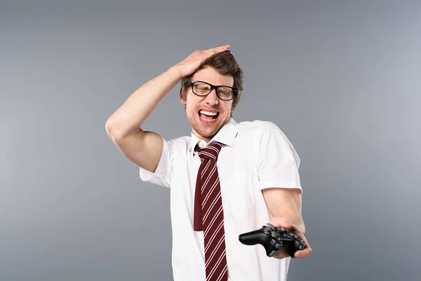 Homme d'affaires excité avec les yeux fermés jouer jeu vidéo avec joystick sur fond gris — Photo de stock