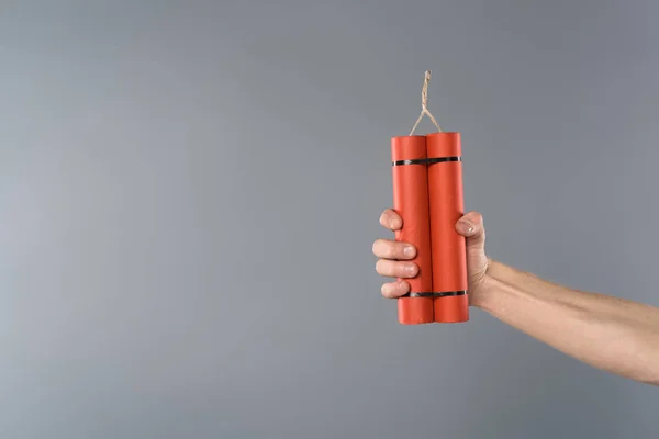 Cropped view of man holding dynamite on grey background — Stock Photo