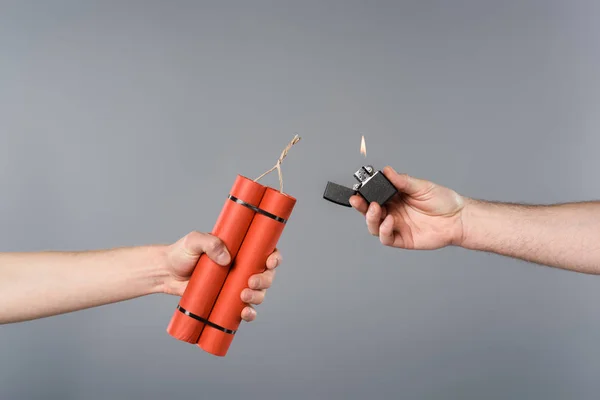 Cropped view of men holding dynamite and lighter on grey background — Stock Photo