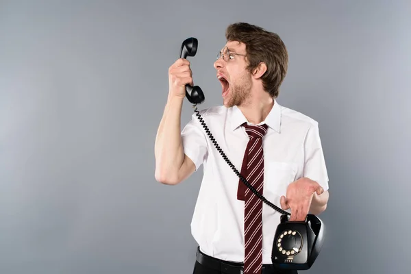 Angry businessman in glasses yelling in vintage phone — Stock Photo