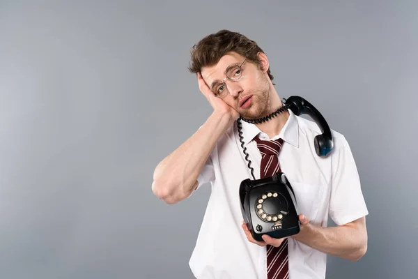 Erschöpfter Geschäftsmann in Brille mit Oldtimer-Handy auf grauem Hintergrund — Stockfoto