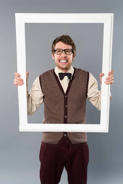 Sad man holding white frame on grey background — Stock Photo