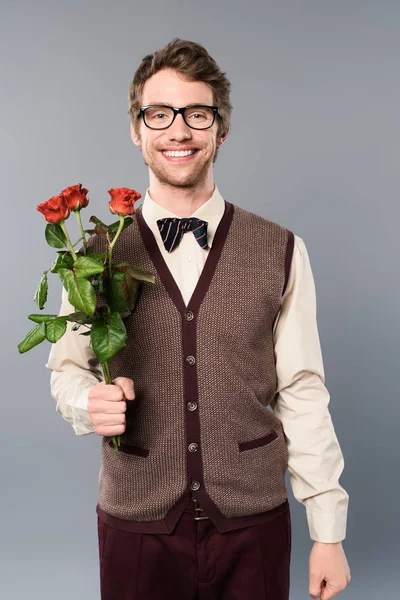 Smiling man holding bouquet of roses on grey — Stock Photo