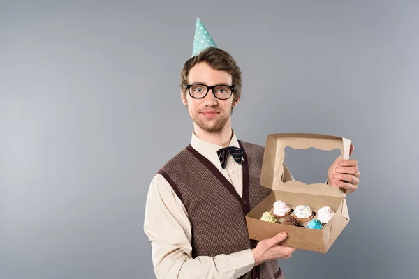 Uomo sorridente in occhiali e scatola di contenimento del cappuccio del partito con i cupcakes — Foto stock
