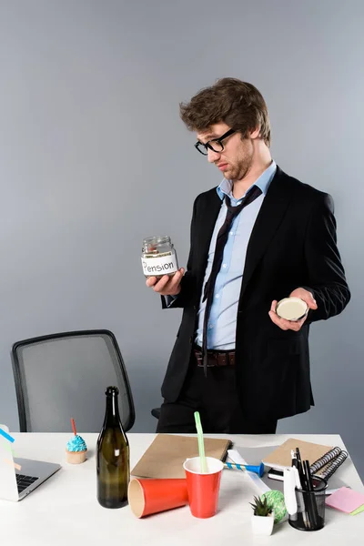 Hombre de negocios borracho en gafas mirando la caja de dinero de pensiones aislado en gris - foto de stock