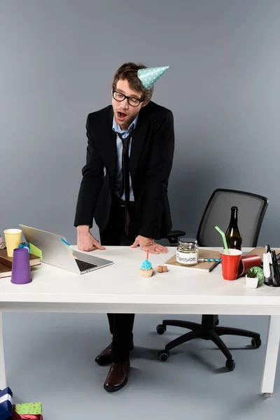 Bâiller homme d'affaires dans la casquette de partie debout près du lieu de travail — Photo de stock