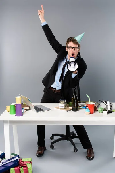 Empresario emocionado gritando en altavoz en el lugar de trabajo - foto de stock