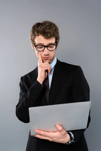 Businessman in suit using laptop isolated on grey — Stock Photo